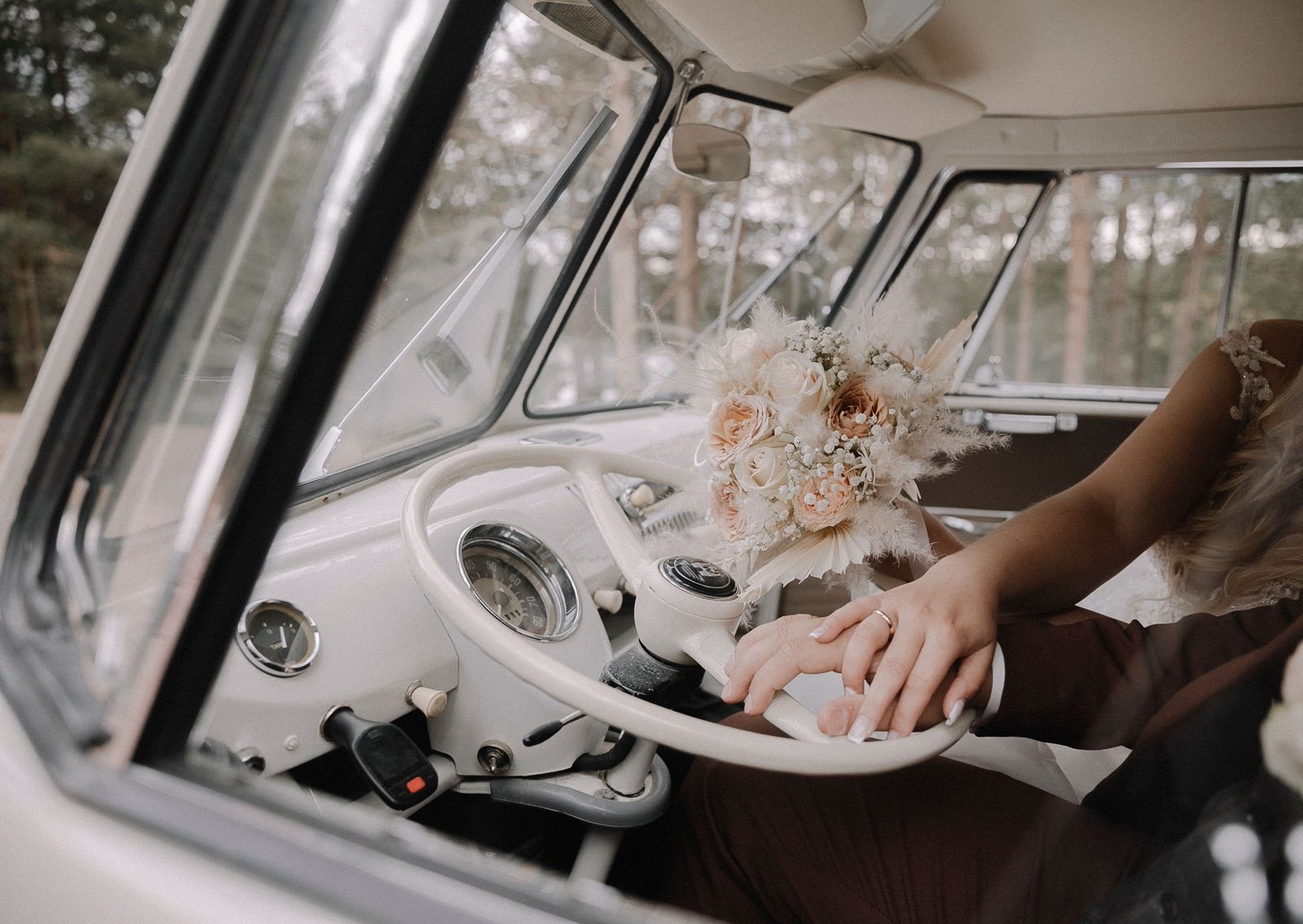 Newlyweds' hands on the wheel of a vintage van